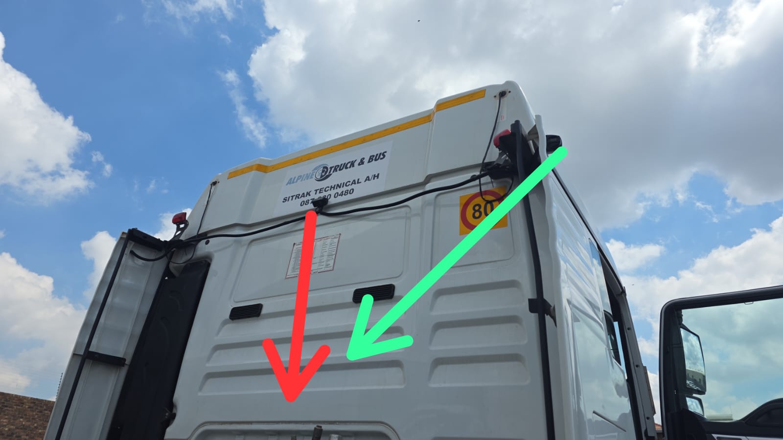 Two Hikvision G40PRO camera units mounted on the back-top of a SITRAK tractor cab — red arrow indicating the rear-facing camera, green arrow indicating the trailer-side camera